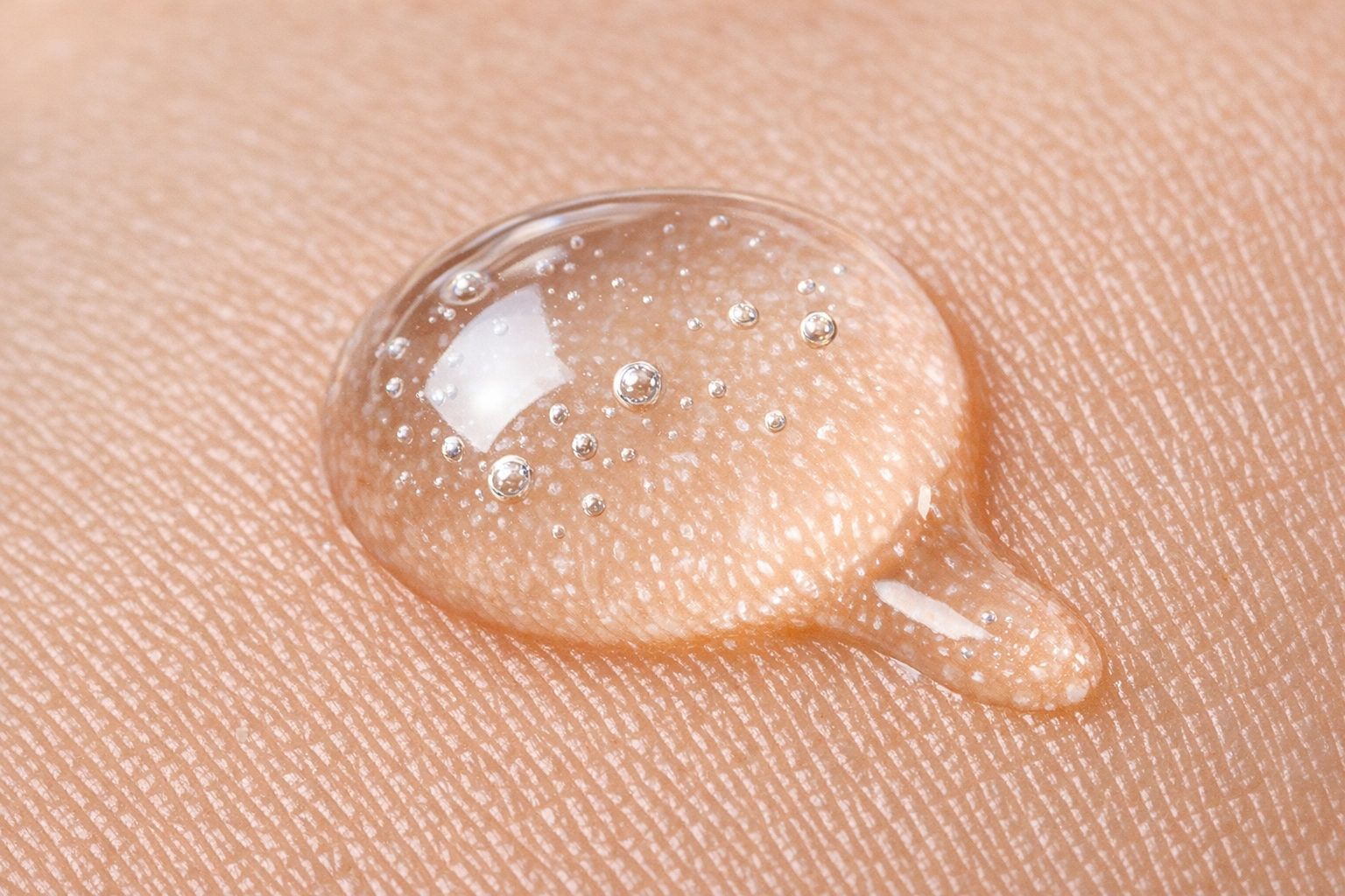 Close-up of a clear hyaluronic acid serum drop on skin to show texture