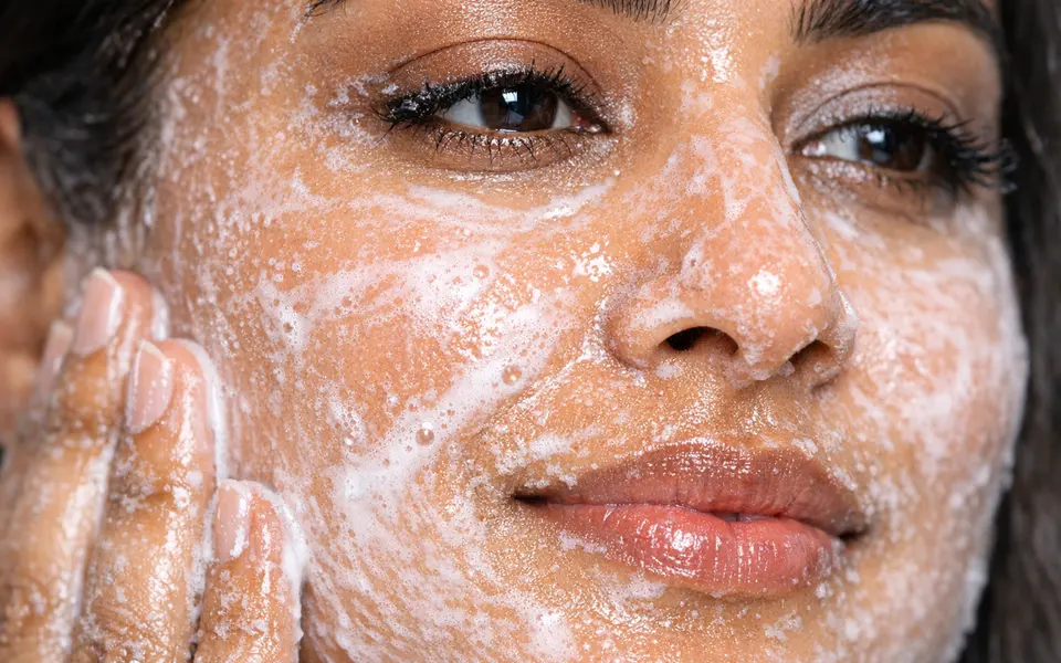 Close-up of an oil-to-milk cleanser emulsifying into a milky texture on an Indian womans face