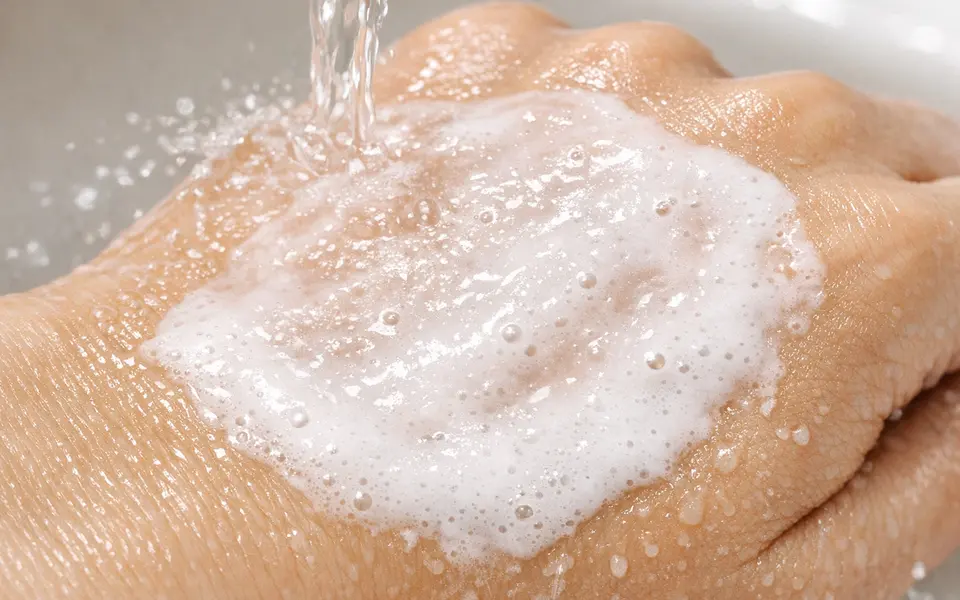 Close-up of an oil cleanser turning milky as water is added to the skin