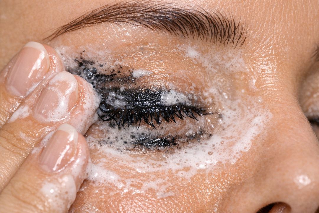 Oil-to-milk cleanser being massaged around the eyes to gently remove waterproof kajal and mascara.